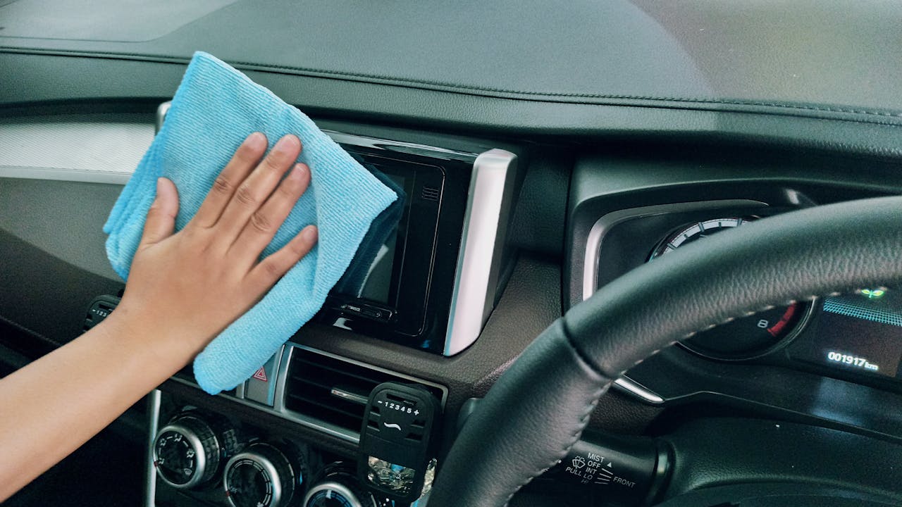 services-03 Crop anonymous person polishing panel in right hand drive car by using blue fiber cloth